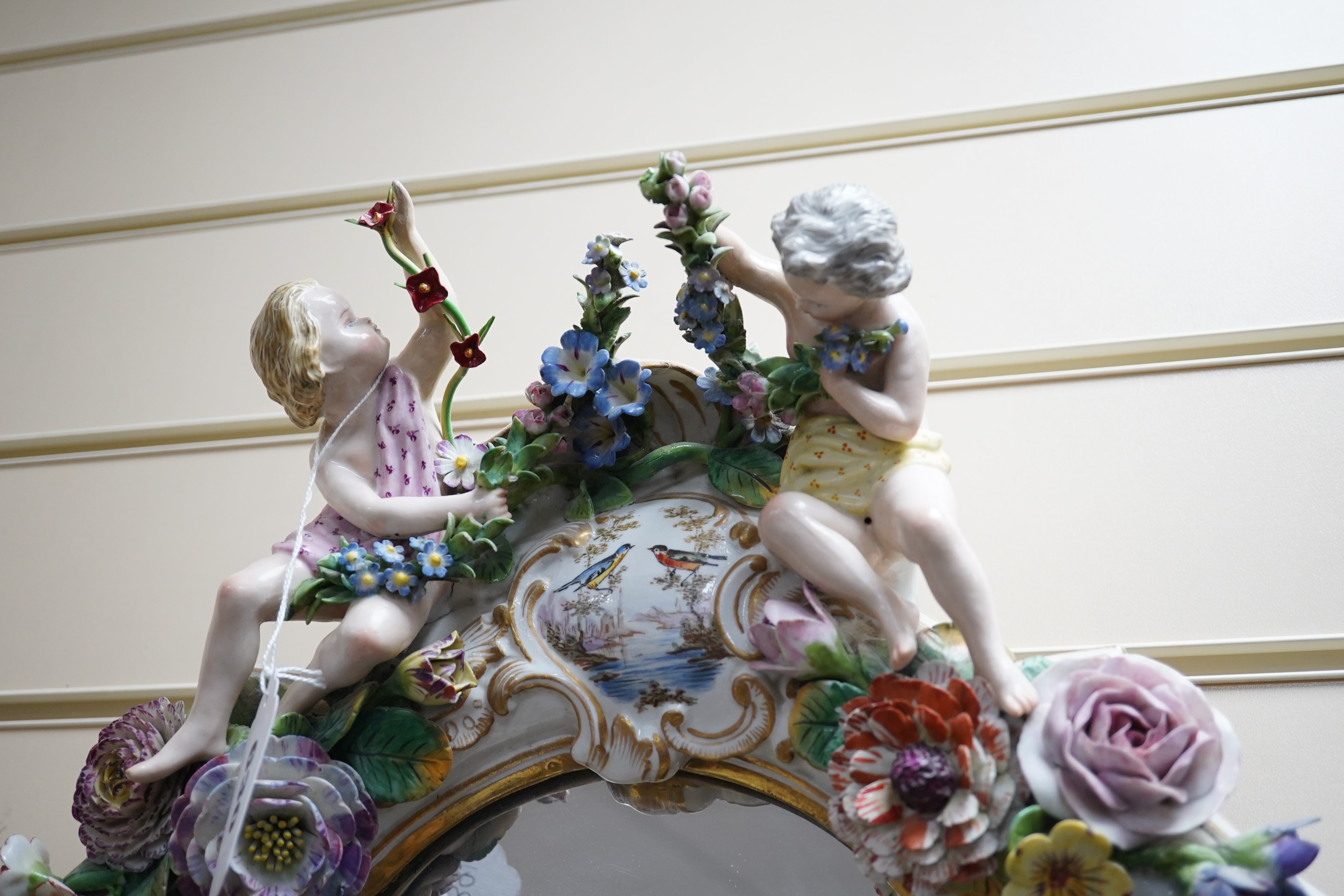 A Meissen style porcelain floral encrusted and figural mirror, 64cm high. Condition - fair, minor losses